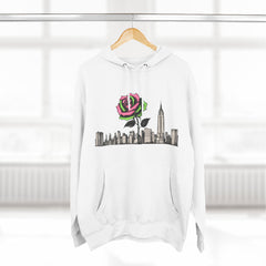 White hoodie with pink rose and NYC skyline graphic, hanging on wood hanger