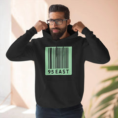 Man wearing black hoodie with green barcode design and 95 EAST text, adjusting hood
