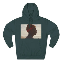 Dark green hoodie with photo graphic of person in orange beanie facing left, beach background.