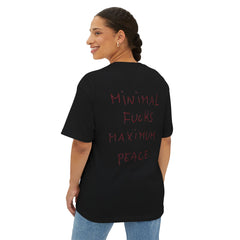 Black oversized t-shirt with red handwritten text: Minimal Fucks Maximum Peace, worn by woman