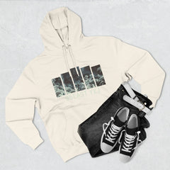 Cream hoodie with graphic print, black jeans, white belt, and black sneakers on a light surface