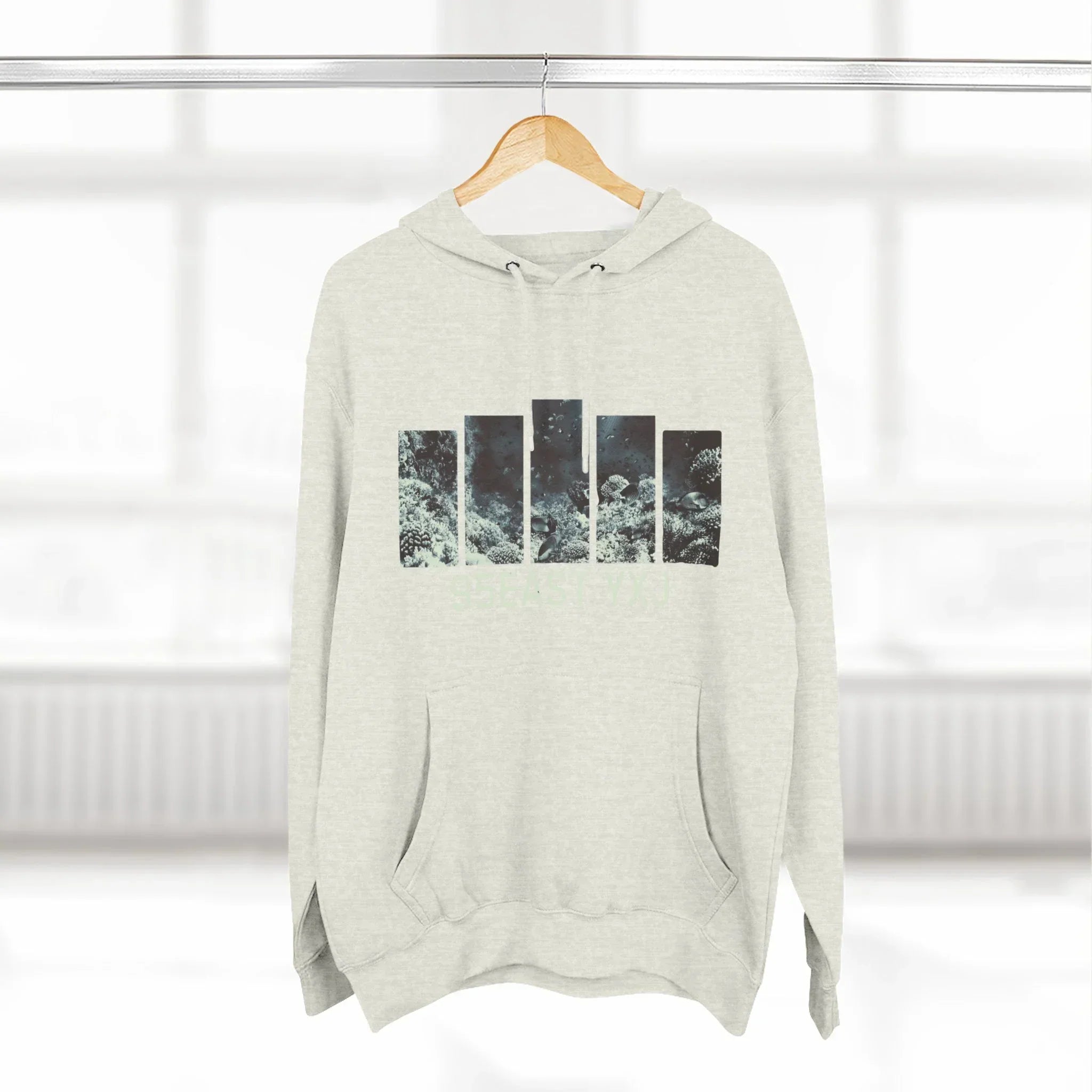 Light grey hoodie with abstract ocean-inspired graphic on front, displayed on hanger indoors