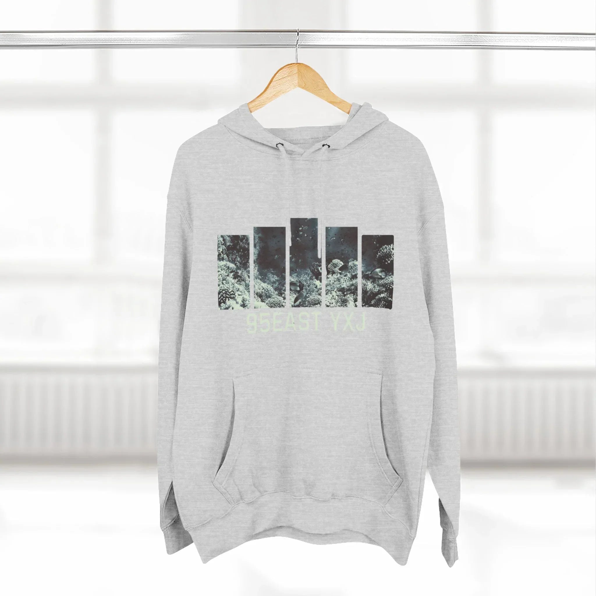 Light grey hoodie with abstract block graphic and '95EAST YXJ' text, hanging indoors