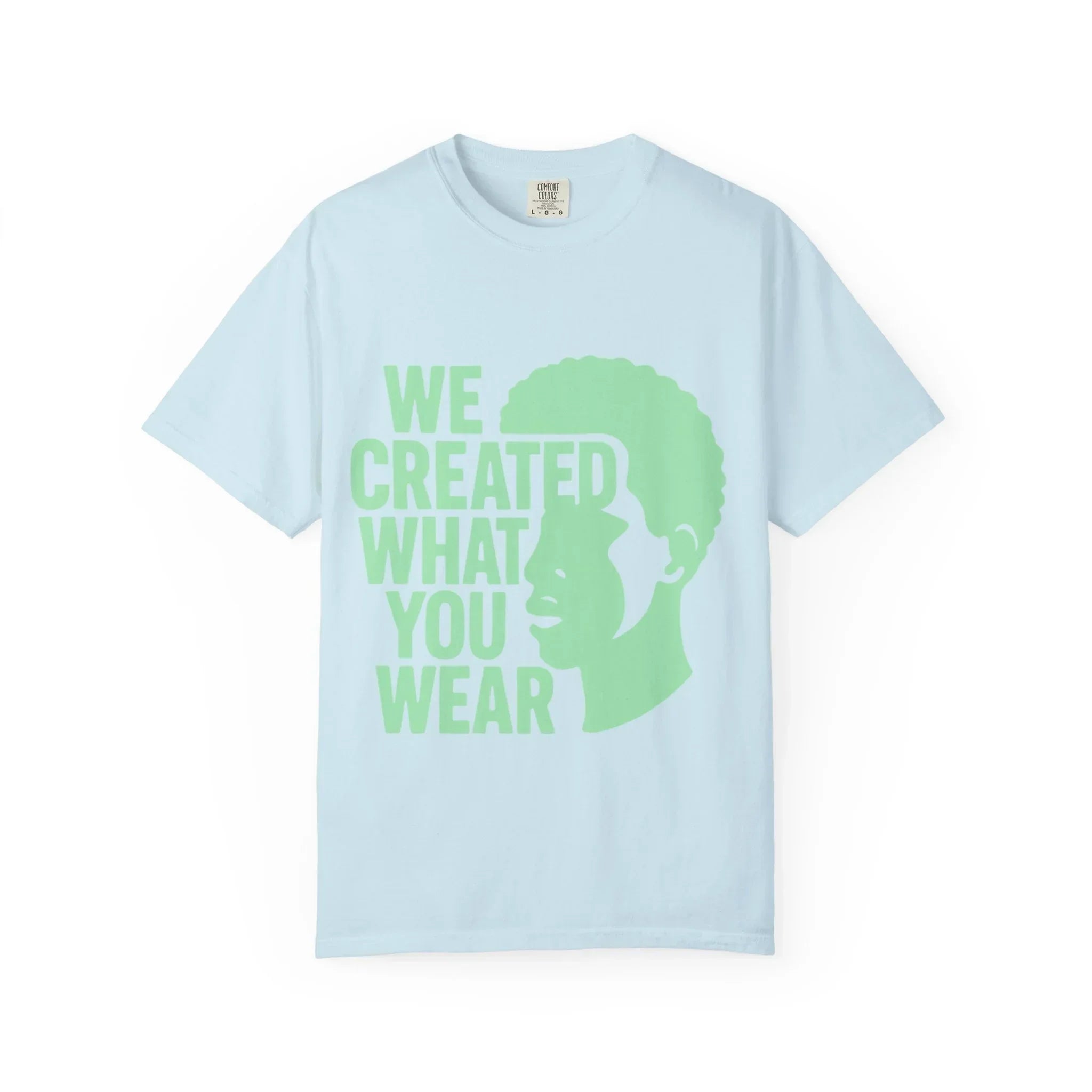 Light blue t-shirt with green text 'WE CREATED WHAT YOU WEAR' and silhouette design