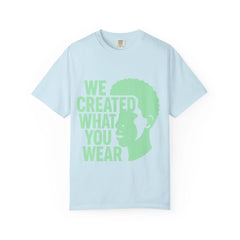 Light blue t-shirt with green text 'WE CREATED WHAT YOU WEAR' and silhouette design