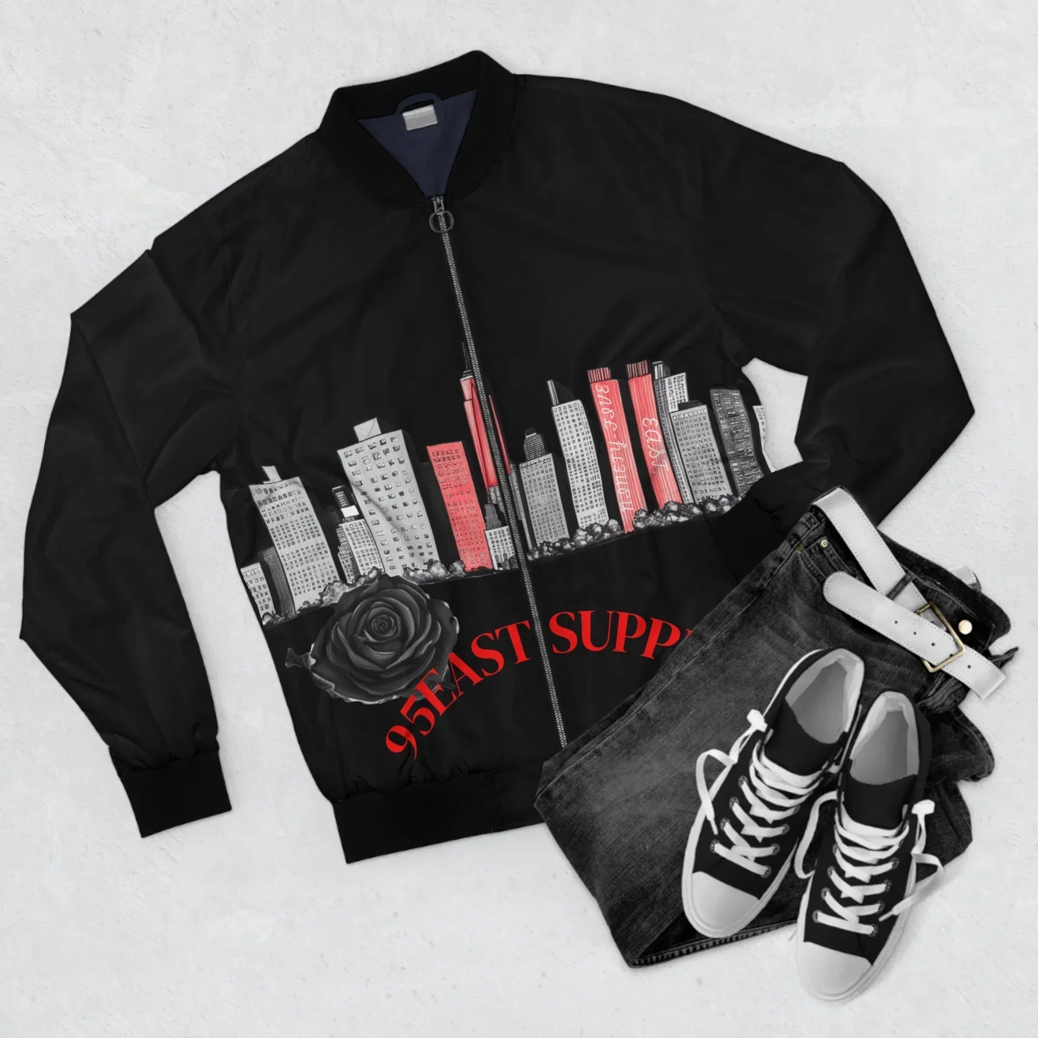 Black bomber jacket with cityscape print, rose, and '95EAST SUPP' text, paired with jeans and sneakers