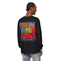 Man wearing black long sleeve shirt with colorful graffiti text 'We Are Human First' on back
