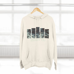 Beige hoodie with abstract black print and '95EAST YXJ' text, hanging on wooden hanger.
