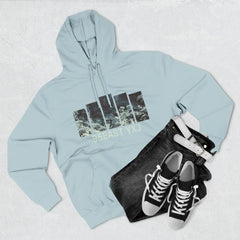 Flat lay of light blue 95EAST YXJ graphic hoodie, black jeans, white belt, and black sneakers.
