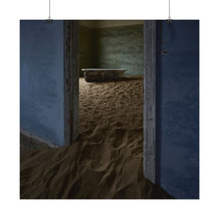 Abandoned room filled with sand, rusted bathtub, peeling blue walls, and weathered doorway