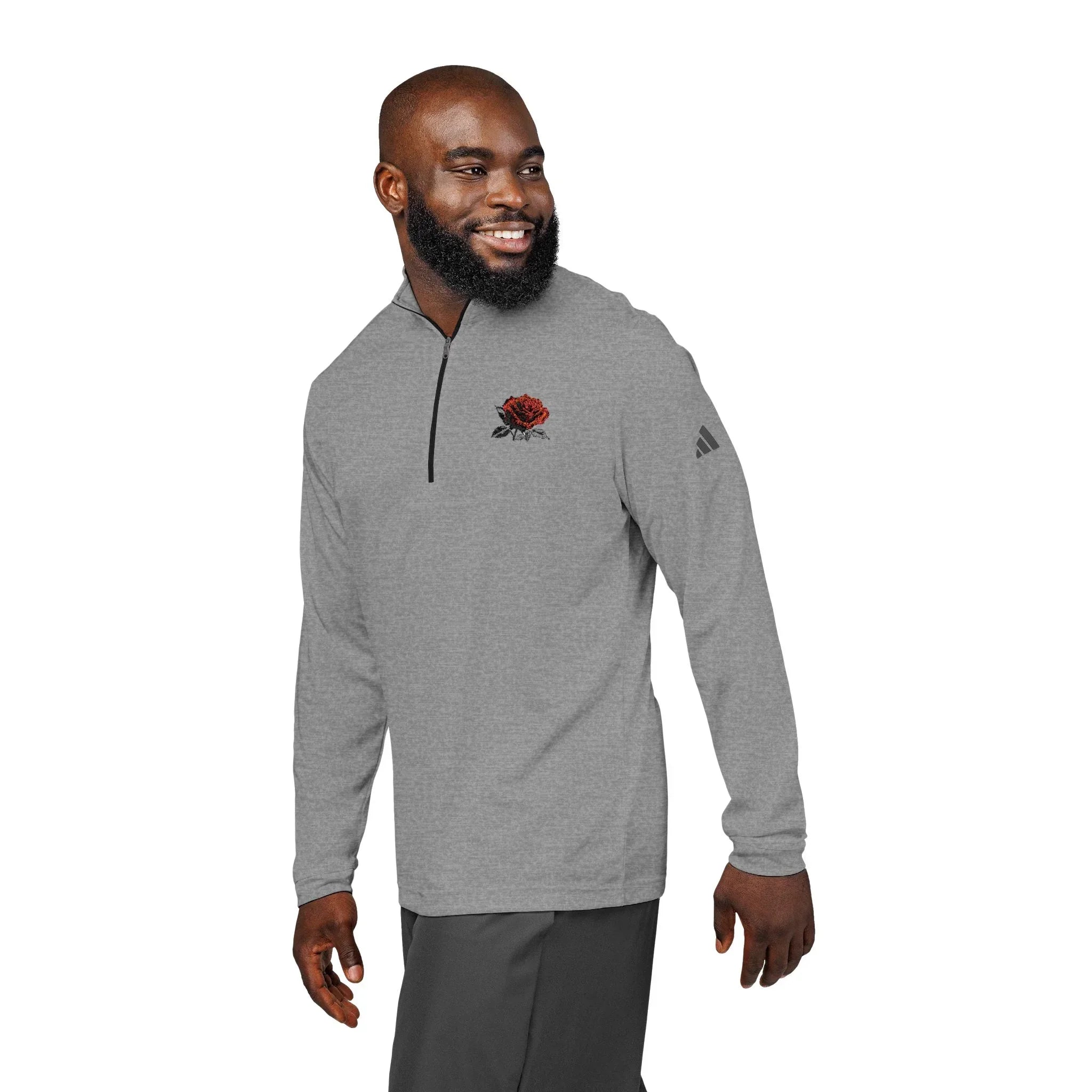 Man wearing gray quarter-zip pullover with embroidered red rose design on chest, isolated.