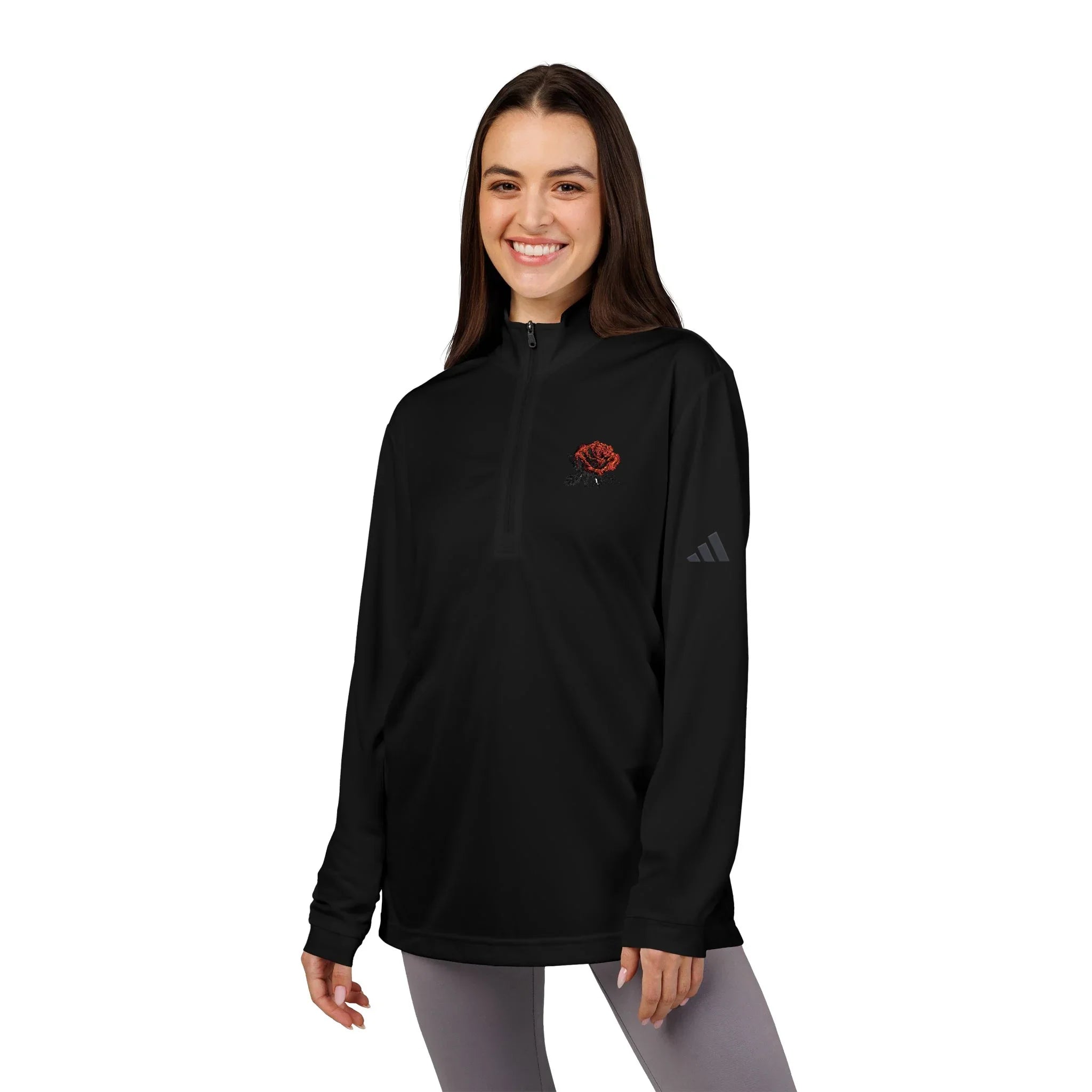Woman wearing a black quarter-zip pullover with a red rose embroidered on the chest.