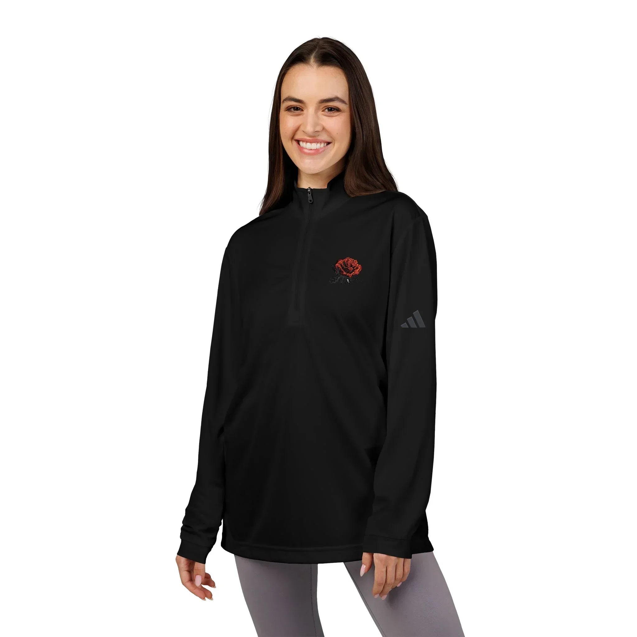 Woman wearing a black quarter-zip pullover with a red rose embroidered on the chest.