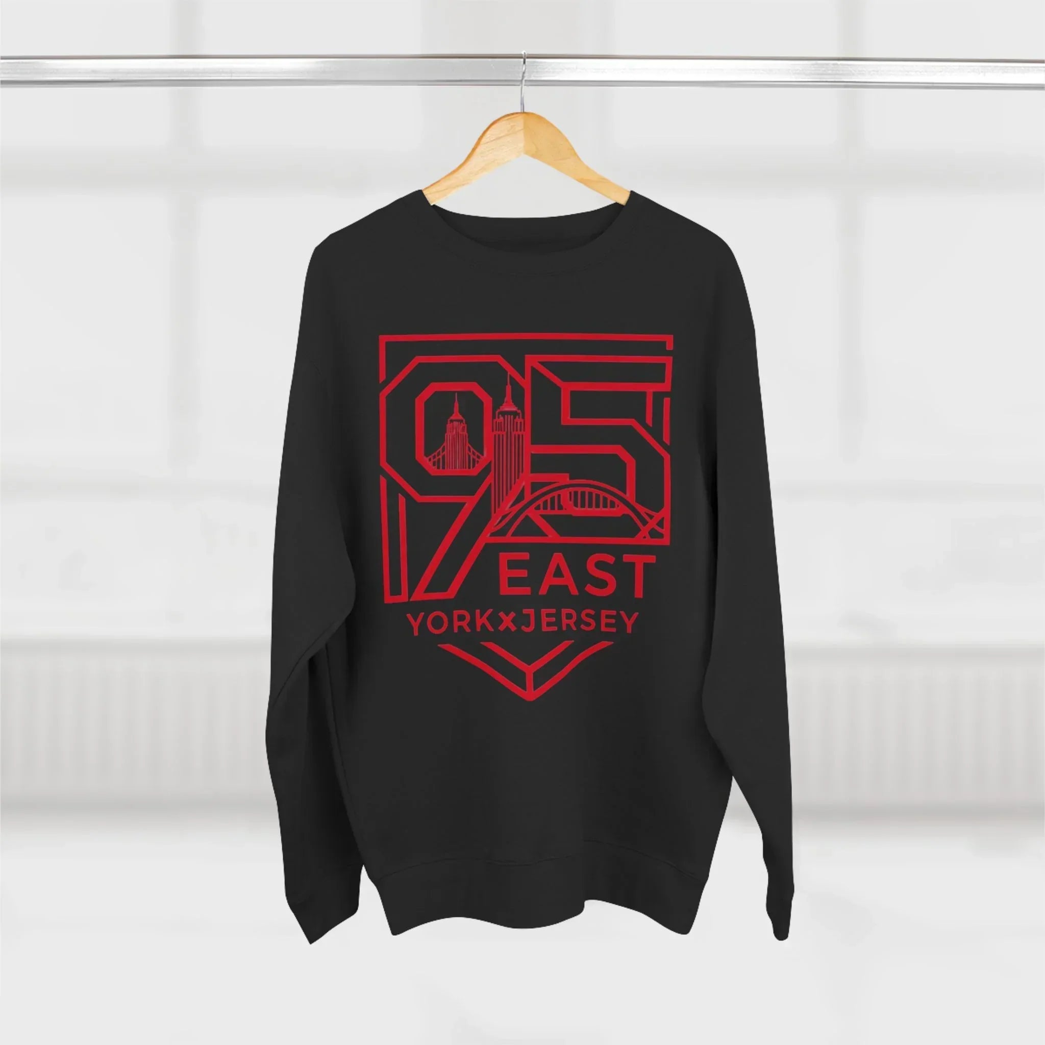 Black hoodie with bold red 95 East YorkxJersey graphic, featuring city skyline design, hanging on wooden hanger