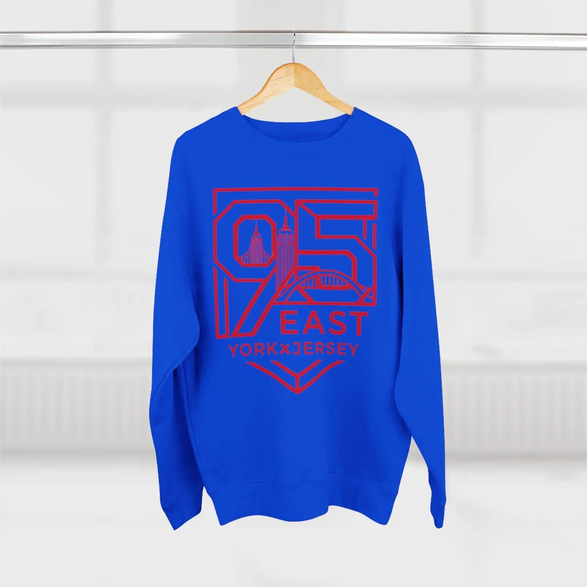 Blue hoodie with red 95 East YorkxJersey graphic, featuring skyline design, hanging on wood hanger
