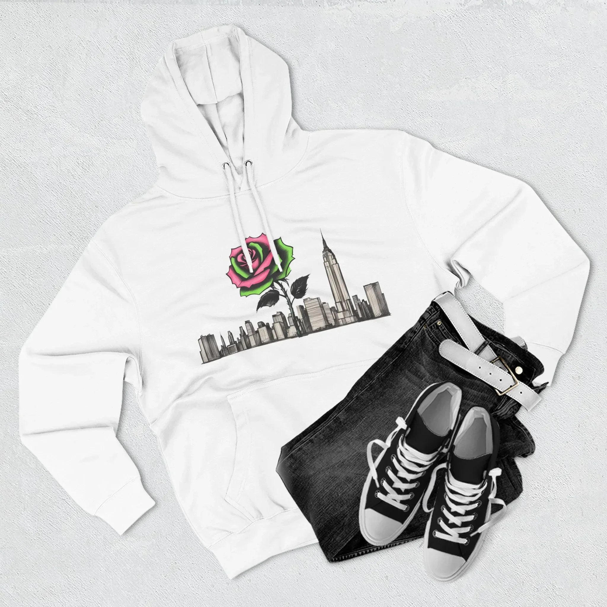 White hoodie with rose and city skyline graphic, paired with black jeans and sneakers