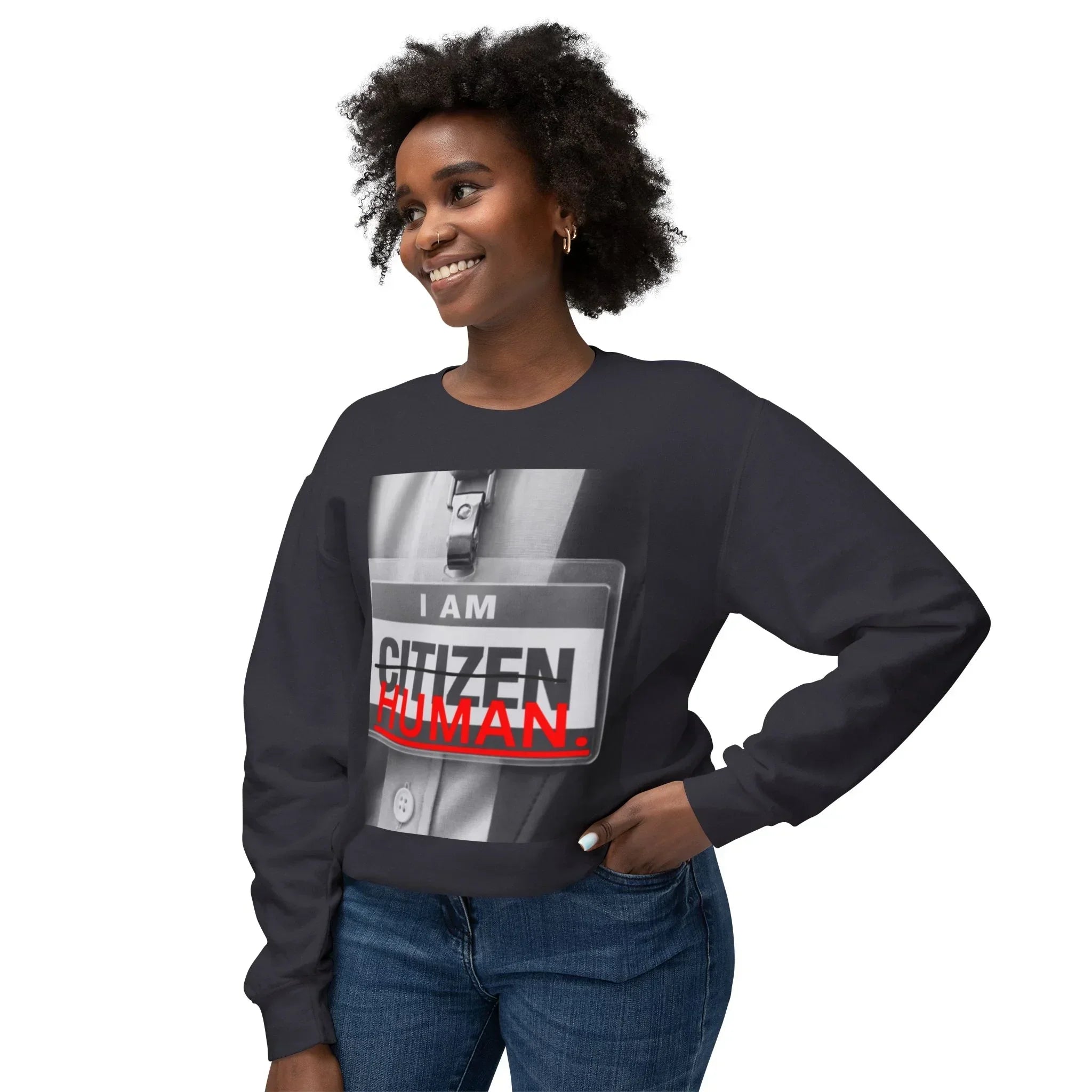 Smiling woman wearing a black sweatshirt with bold 'I AM HUMAN' graphic print and jeans