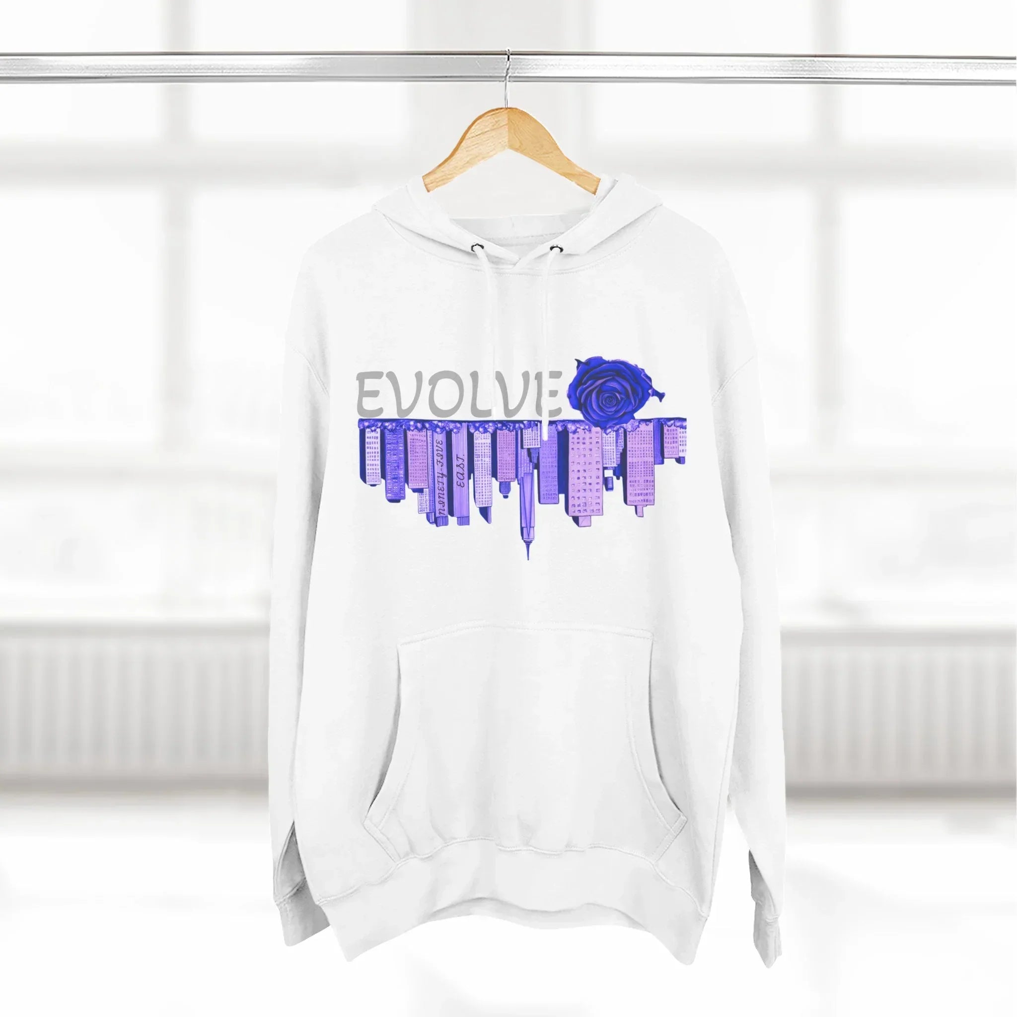White hoodie with 'EVOLVE' text, blue rose, and city skyline graphic, hanging on wood hanger