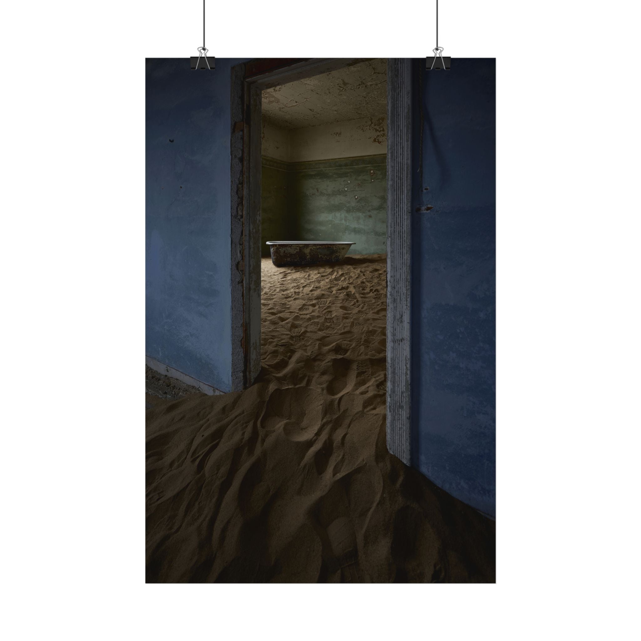 Abandoned room with sand-filled doorway and vintage bathtub, moody blue walls, artistic decay photography