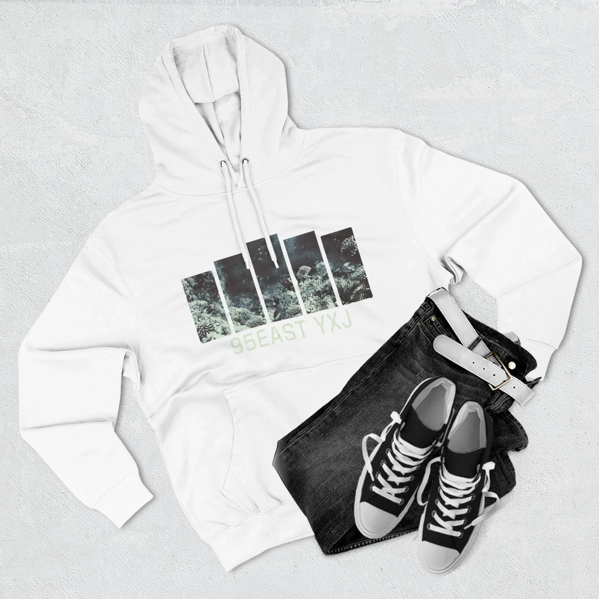 White hoodie with nature graphic and '95EAST YXJ' text, black jeans, sneakers, white belt