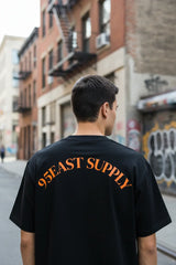 Man wearing black 95EAST SUPPLY t-shirt on urban street with graffiti