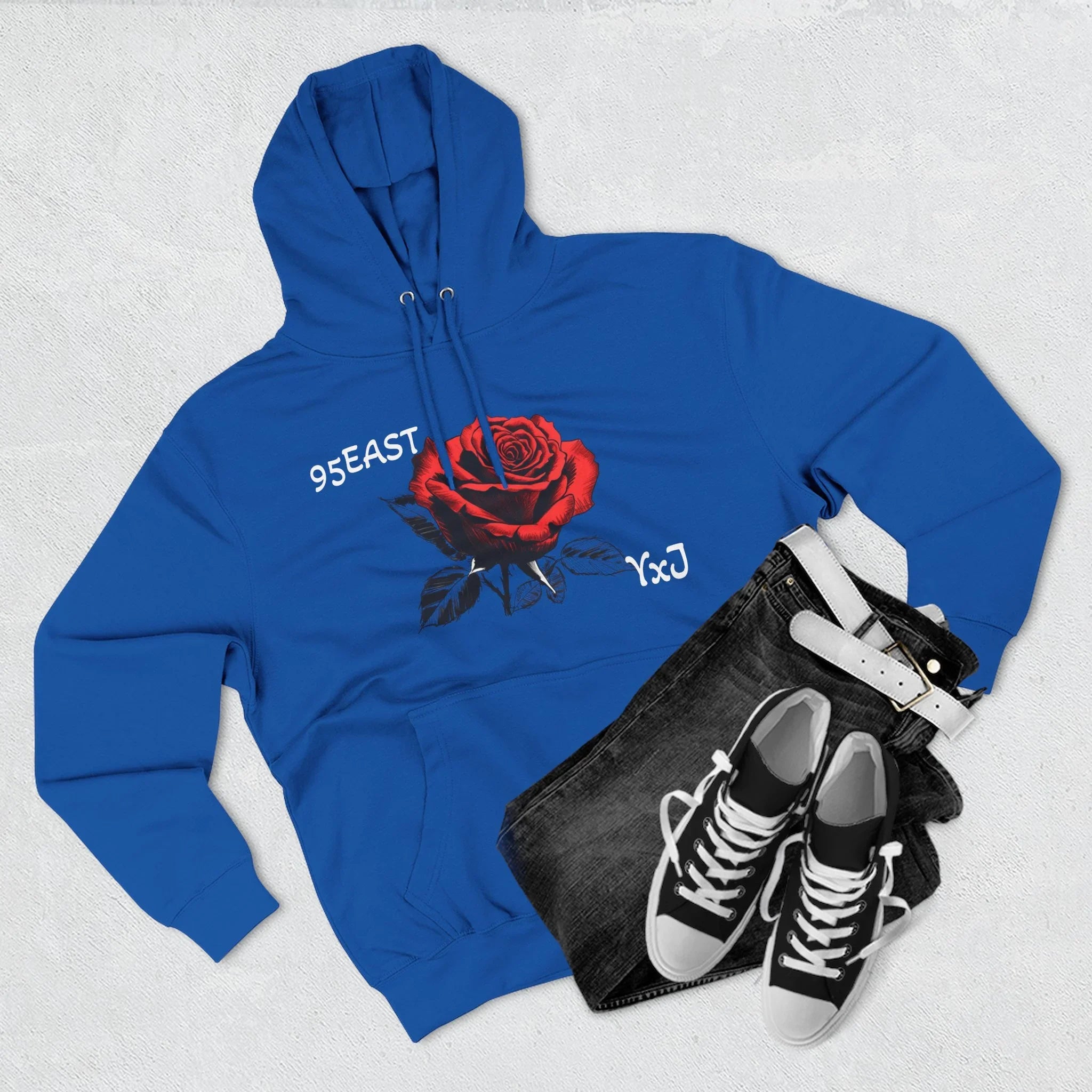 Blue hoodie with red rose graphic and '95EAST YxJ' text, styled with jeans and sneakers