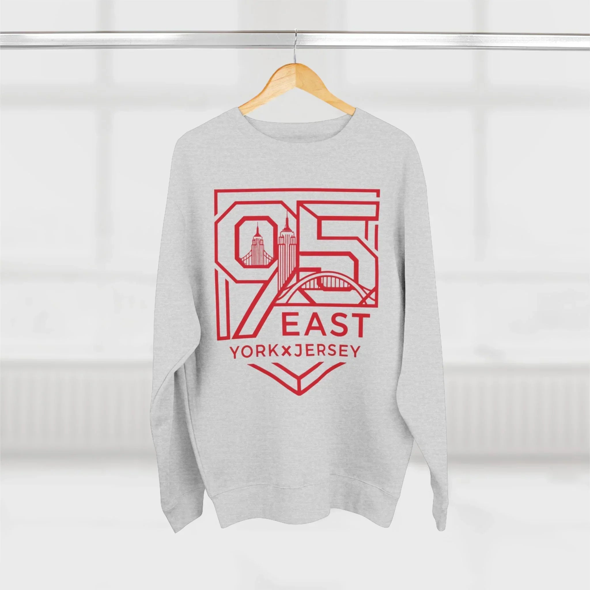 Gray hoodie with red 95 East YorkxJersey graphic, city skyline design, hanging on wood hanger