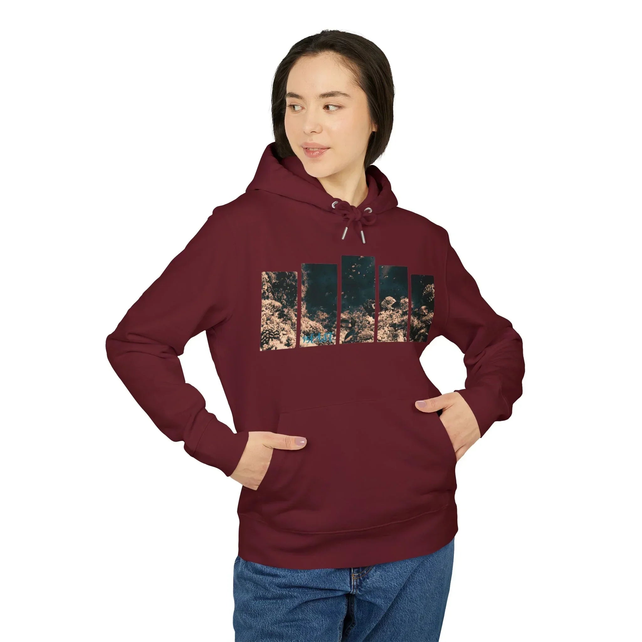 Woman wearing a maroon hoodie with abstract nature graphic, hands in pockets, casual style.