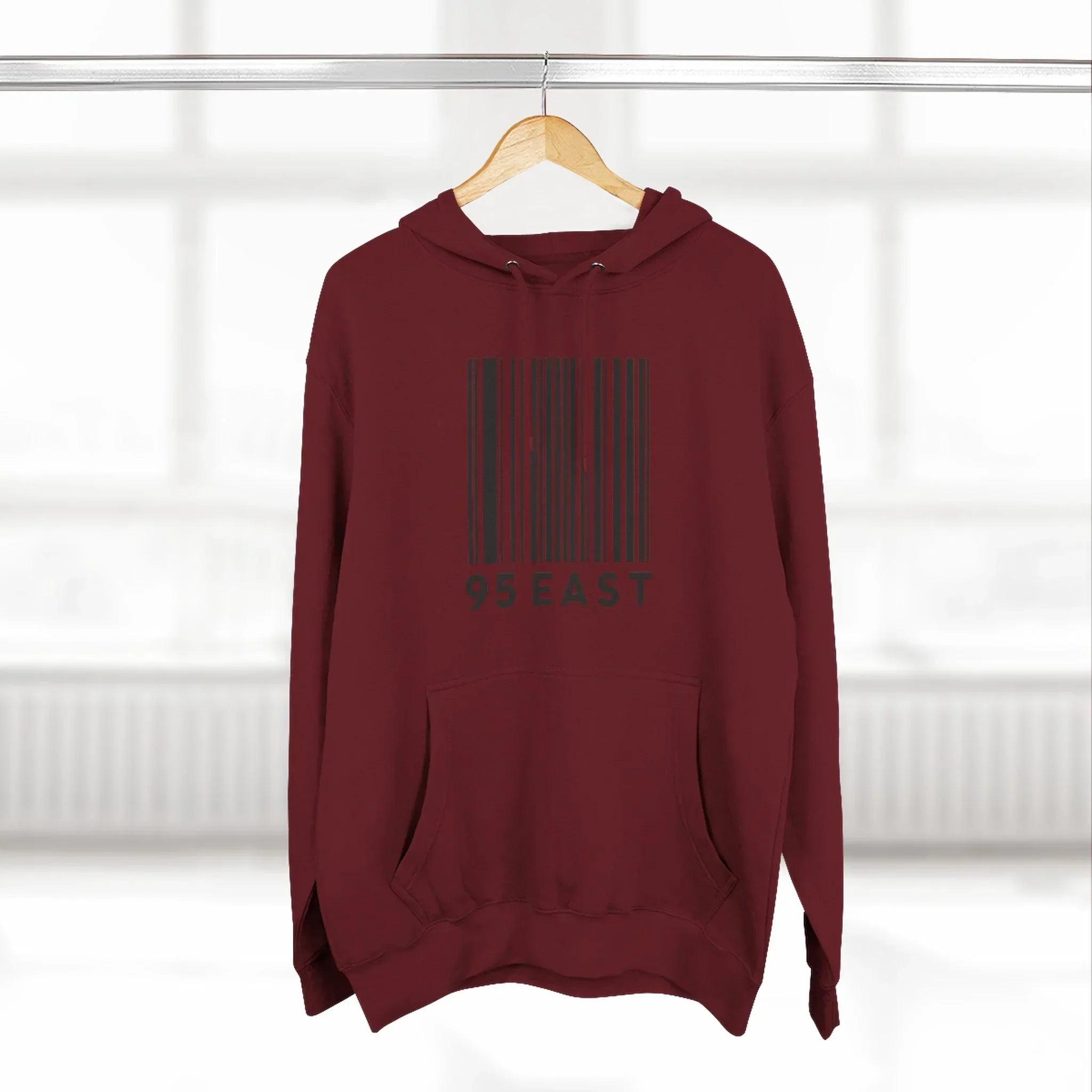 Maroon hoodie with black barcode graphic and 95 EAST text, displayed on hanger indoors
