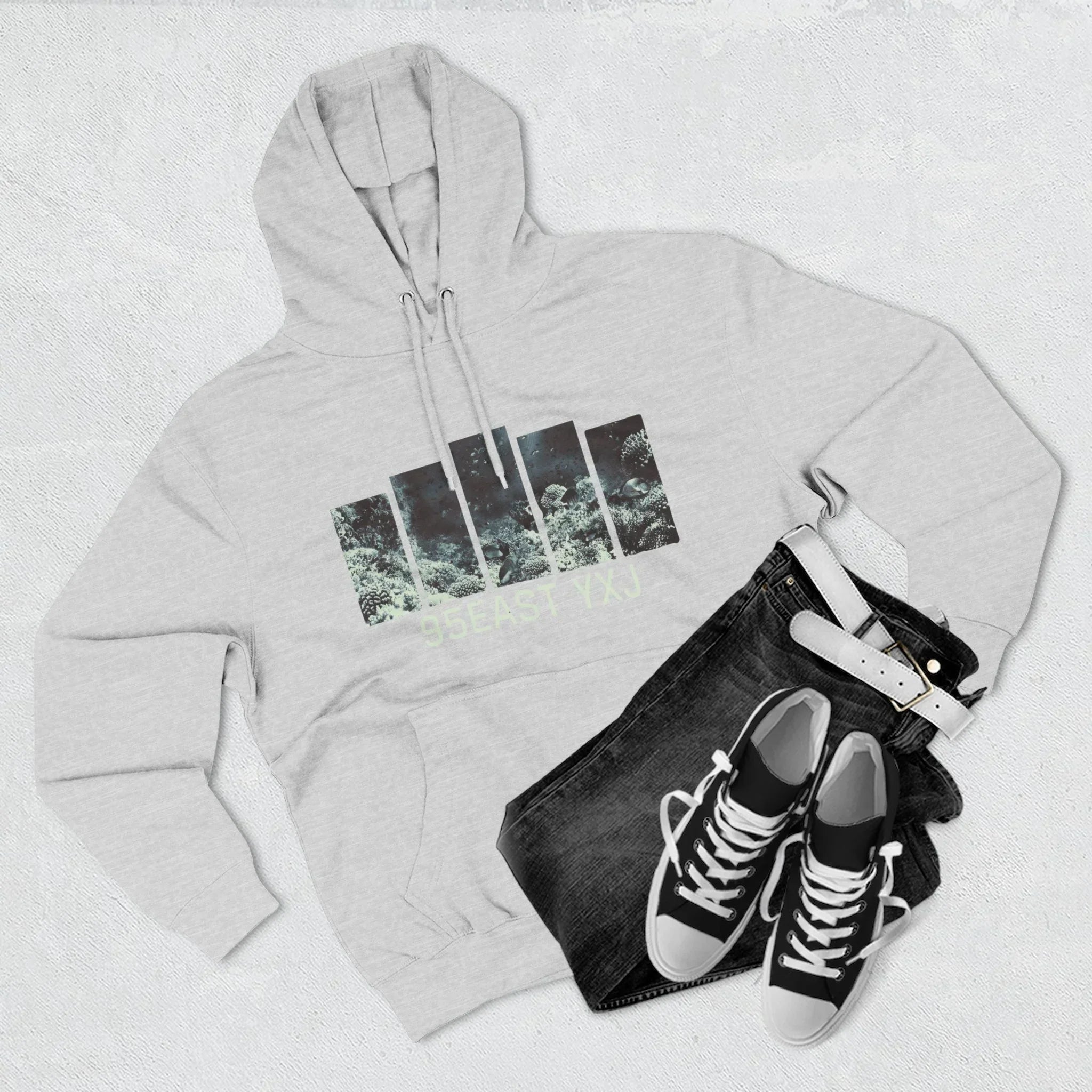 Light gray hoodie with graphic design, black jeans, white belt, and black sneakers laid flat