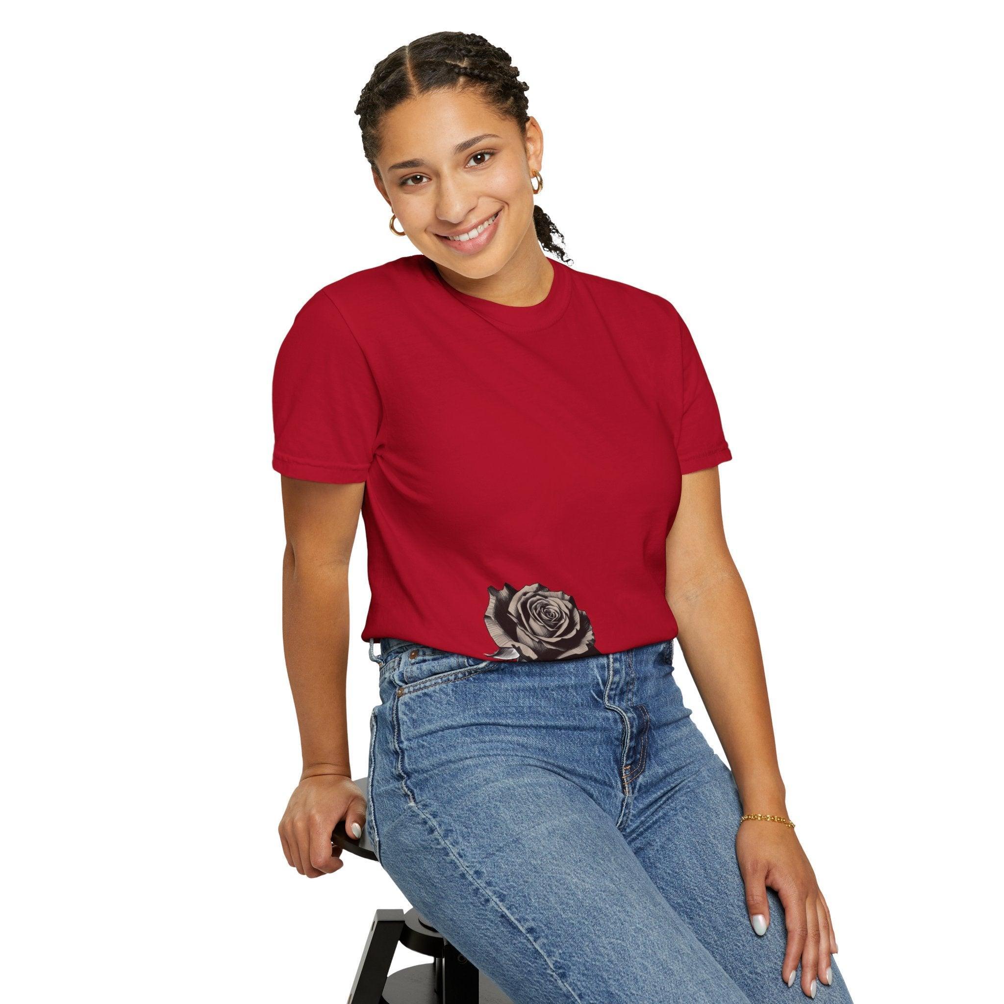 Woman wearing red t-shirt with black rose graphic, paired with blue jeans, smiling confidently