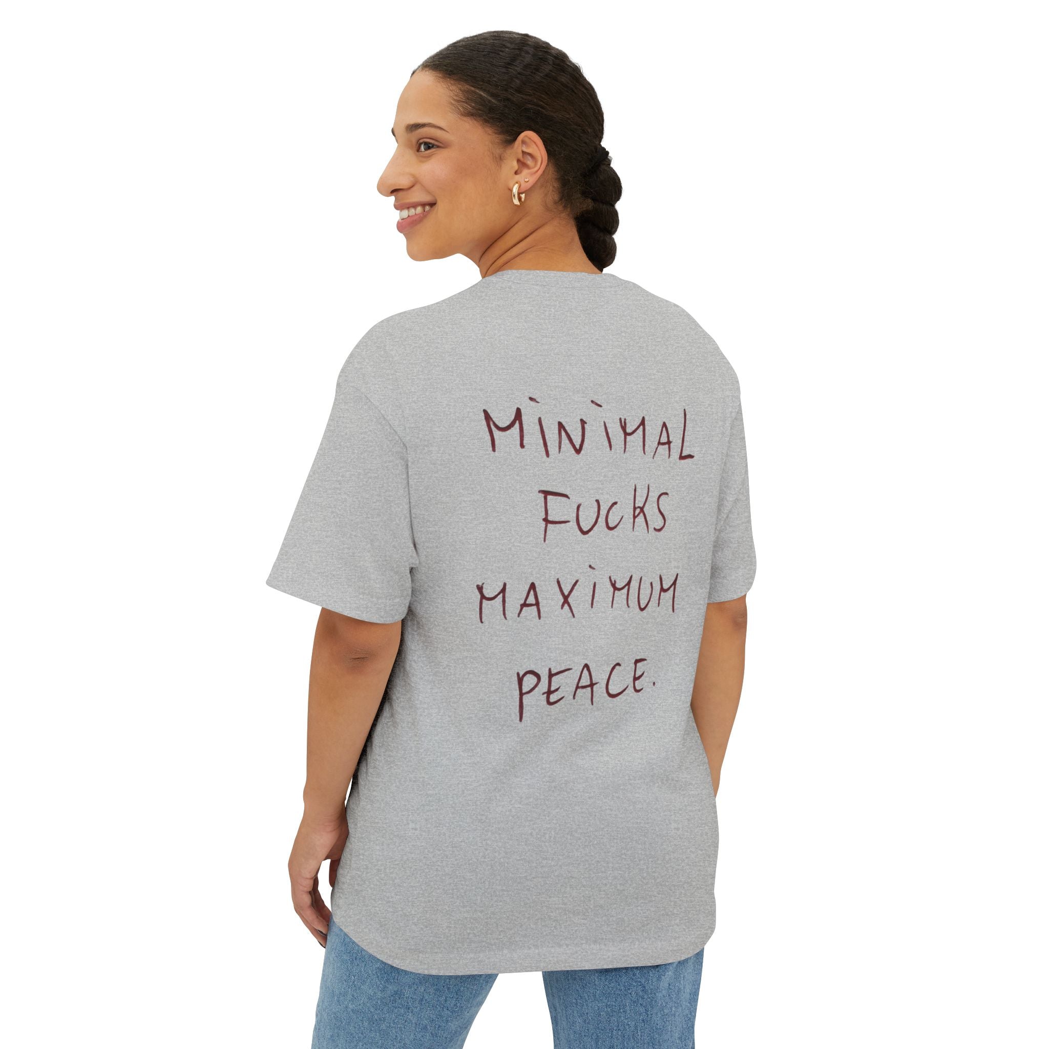 Gray oversized t-shirt with 'Minimal Fucks Maximum Peace' text on back, worn by woman in jeans